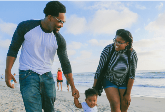 a family walking with their toddler on the beach
